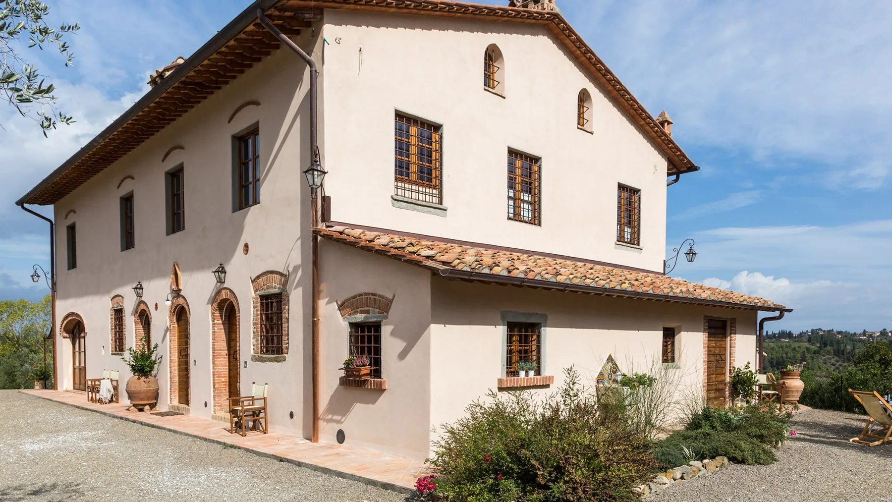 A large stucco building with a tiled roof stands beside a gravel path.
