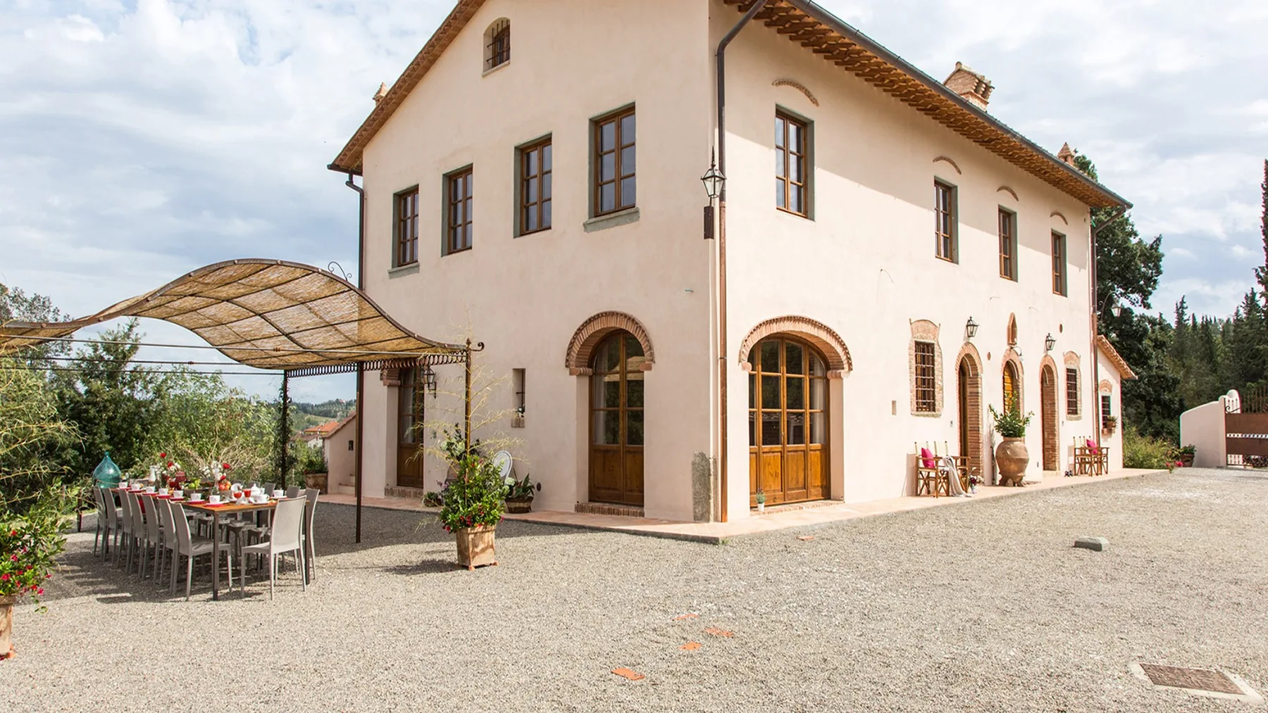 A pale stucco building with arched windows stands beside an outdoor dining area.