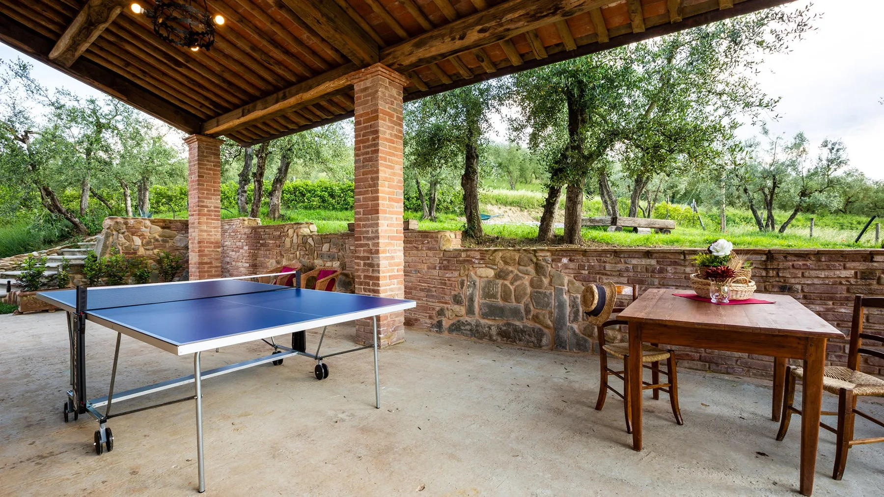 A covered outdoor patio has a table tennis table and wooden dining table.