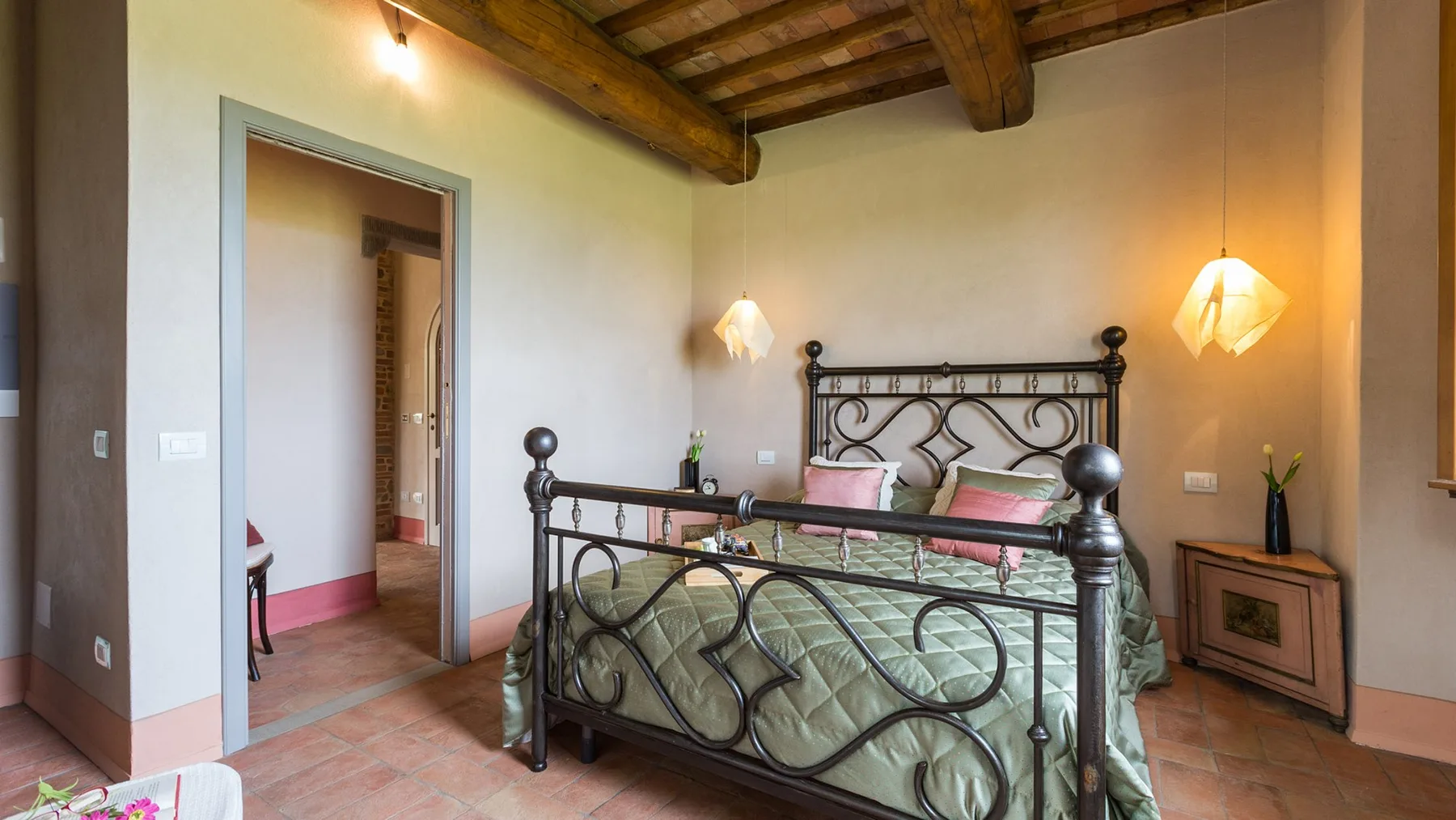 A bedroom with a metal bed, patterned bedding, and exposed wooden ceiling beams.