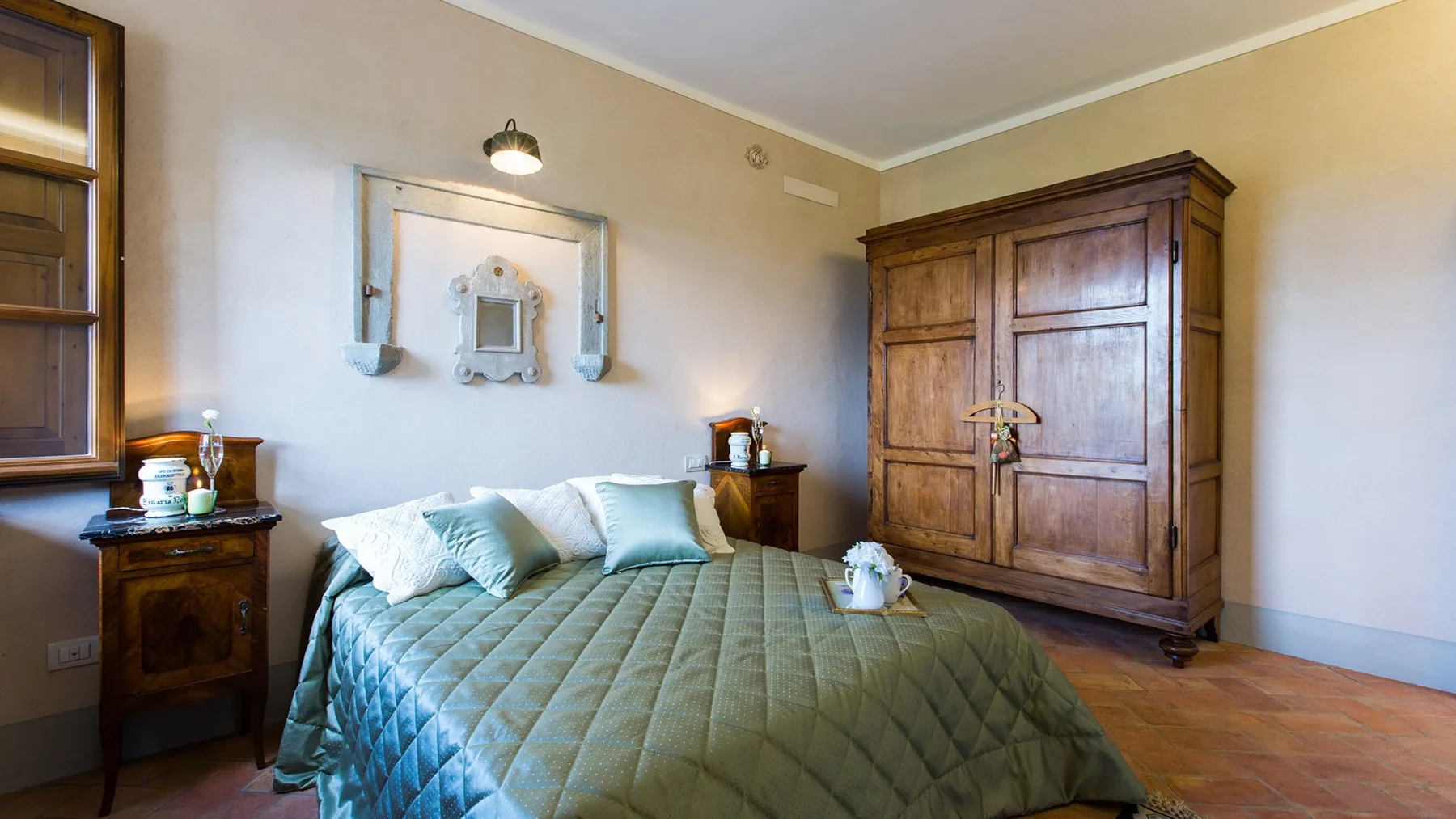 A bedroom with a neatly made bed and a large wooden wardrobe.