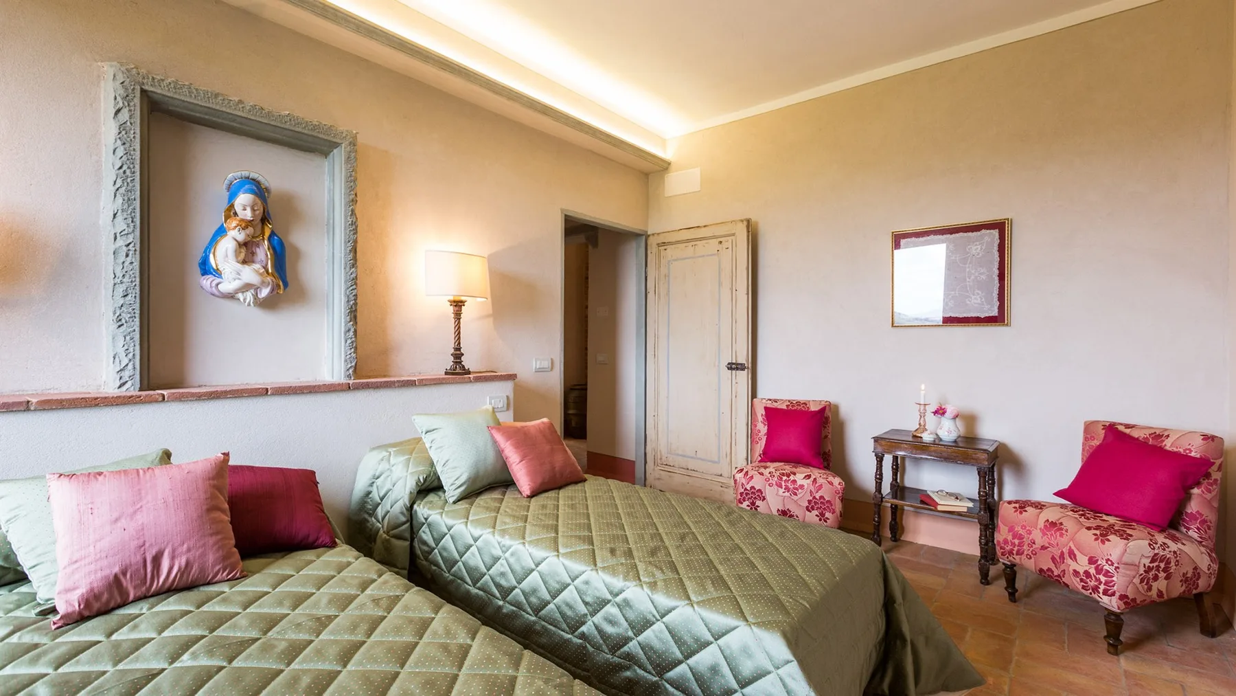 A bedroom with two beds, colorful cushions, and framed wall art.