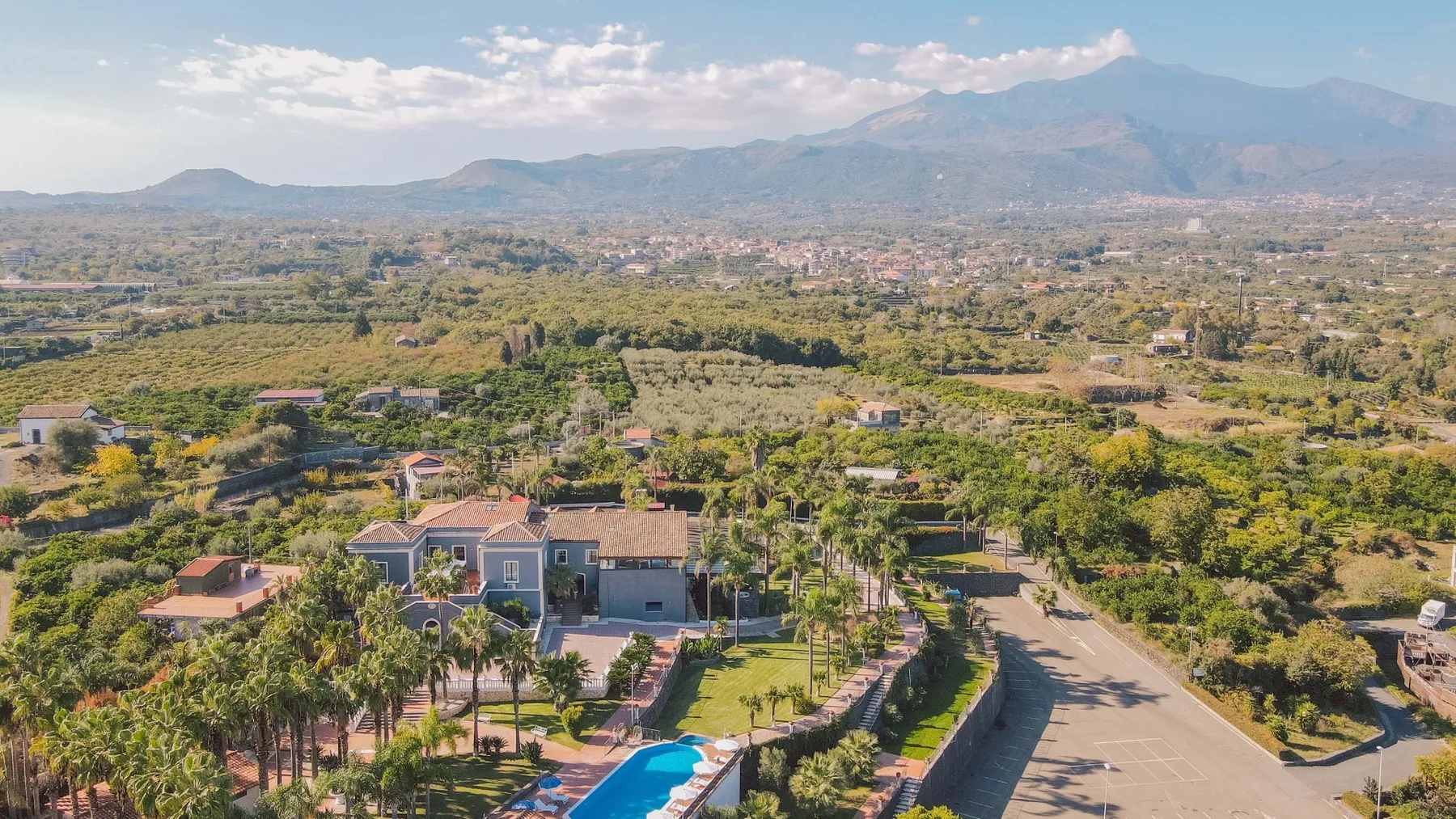 Vista aérea de una propiedad ajardinada con una piscina y montañas a lo lejos.