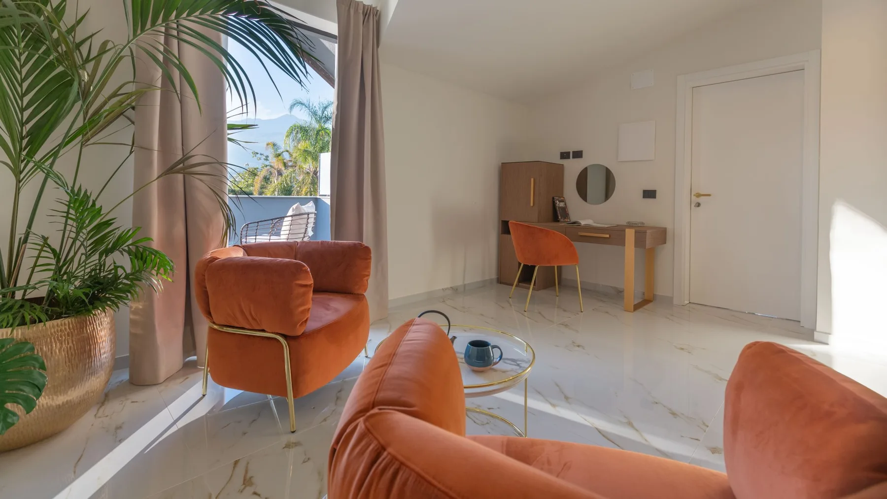 Una luminosa zona de estar con asientos naranjas junto a un pequeño escritorio y una ventana.