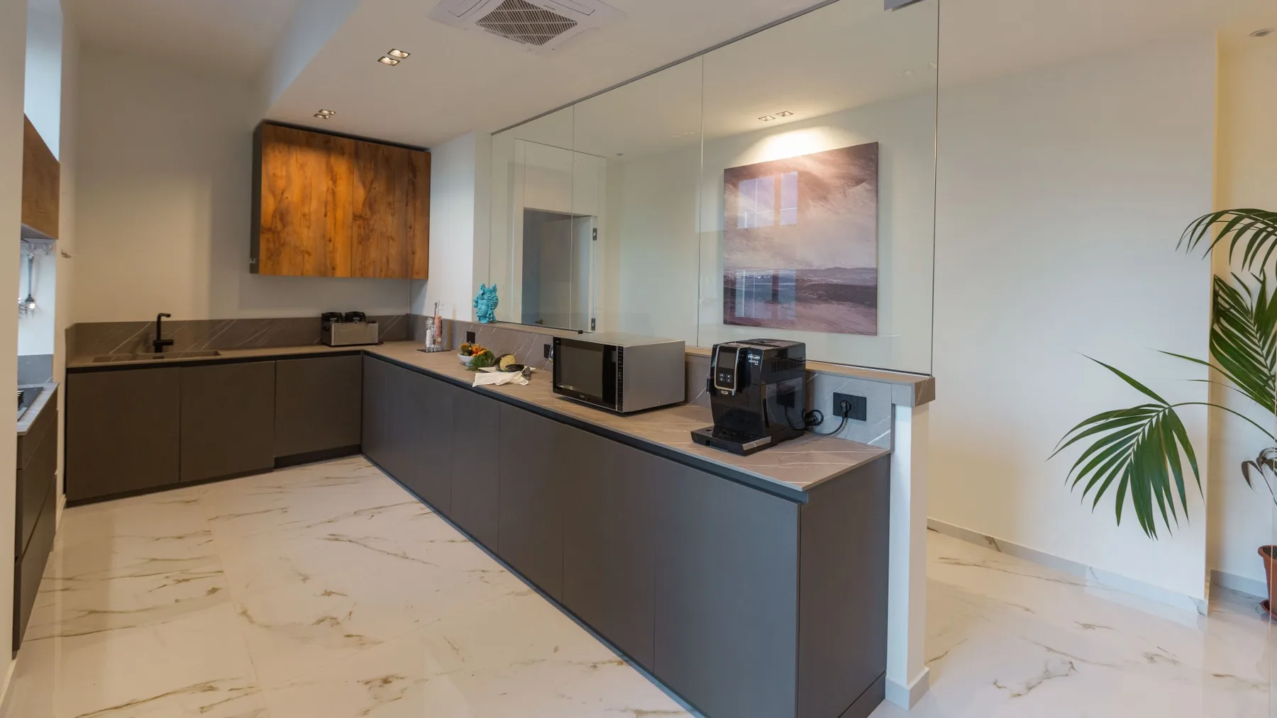 Una cocina moderna con gabinetes oscuros, una encimera central y un cuadro en la pared.