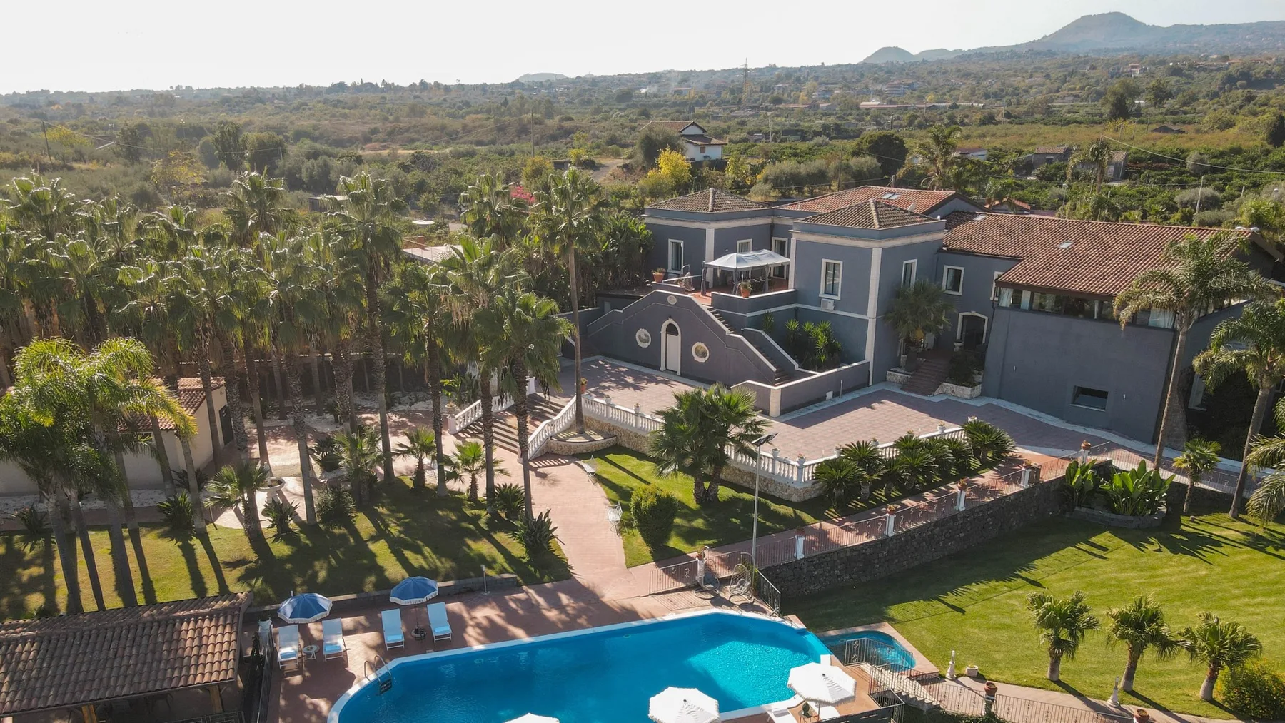 Vista aérea de una propiedad ajardinada con una piscina azul y vegetación alrededor.