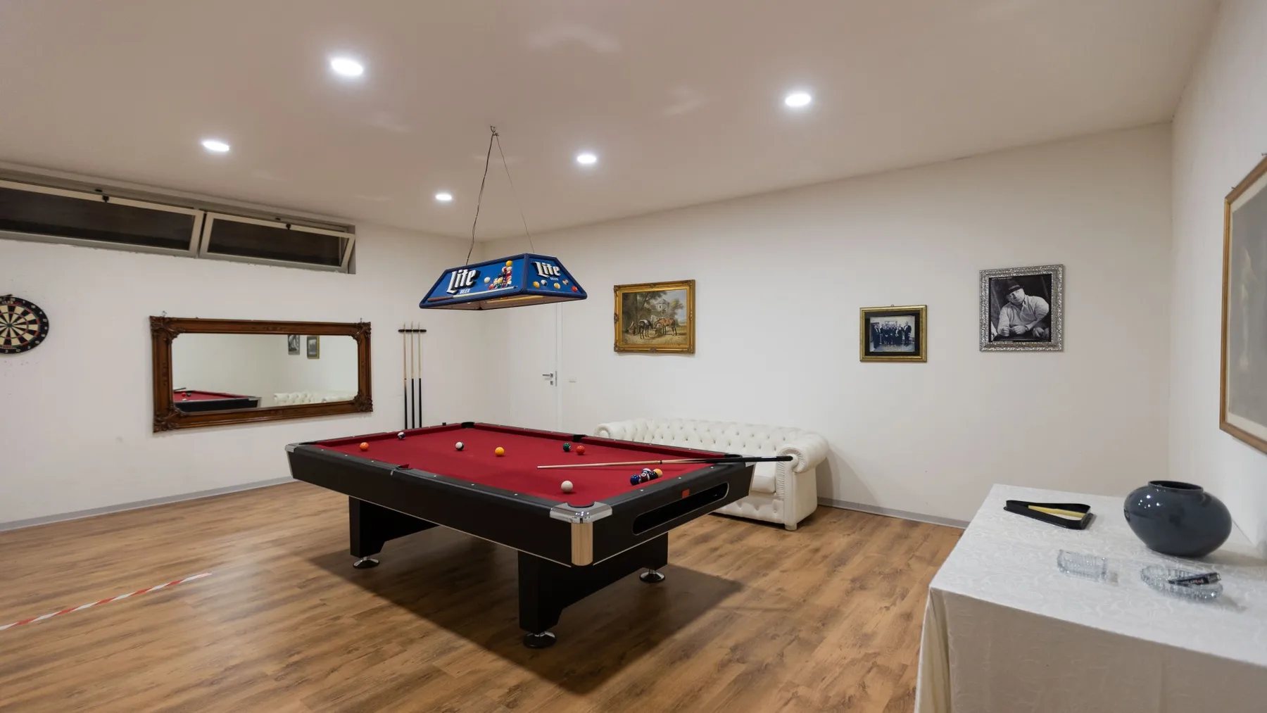 Una sala de billar con una mesa de paño rojo y asientos.
