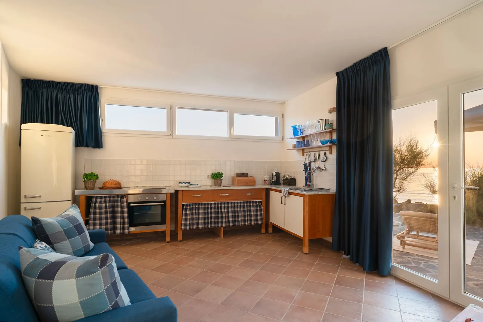 A combined kitchen and seating area with a blue couch and dining table.