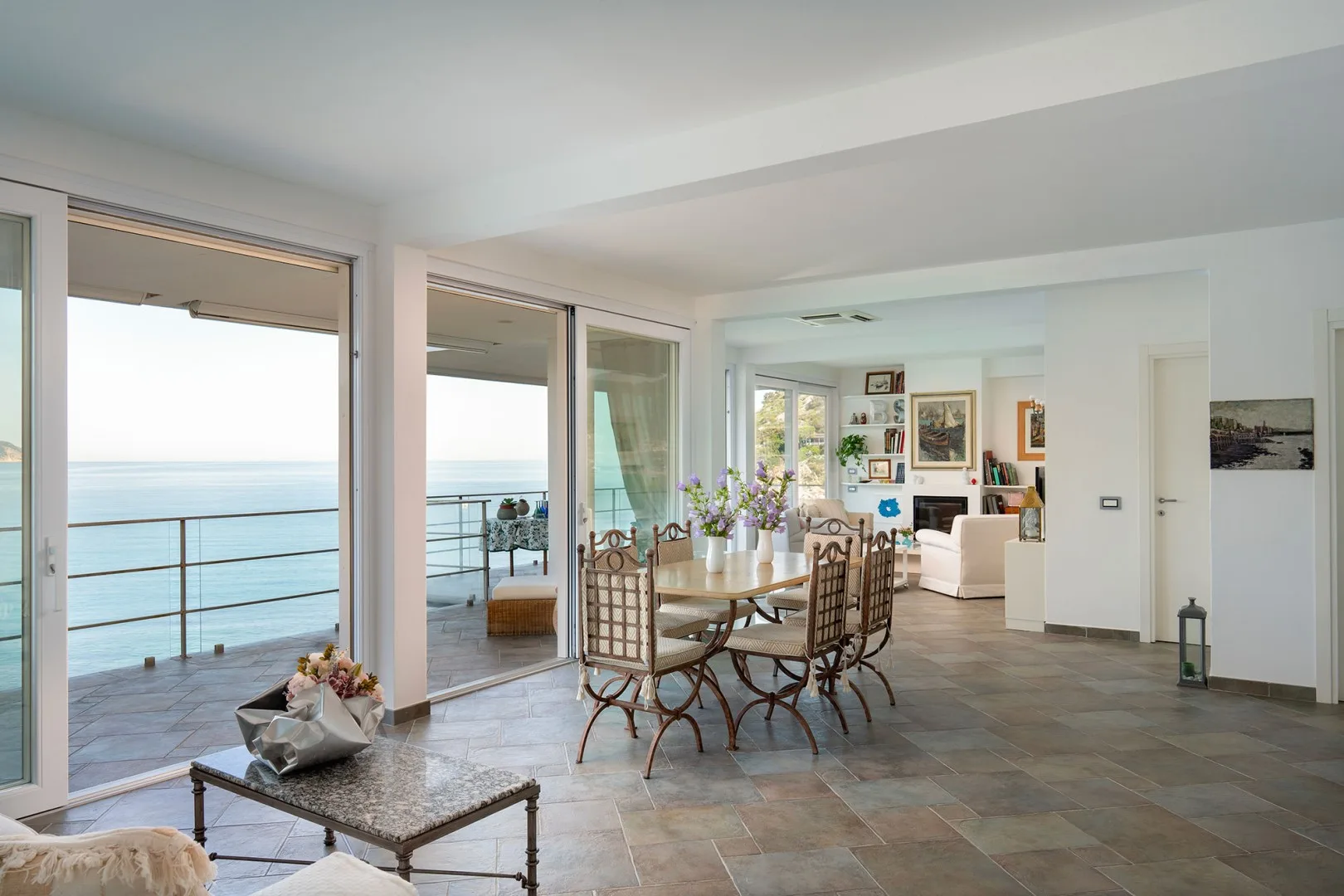 A bright living and dining area opens onto a terrace overlooking the sea.