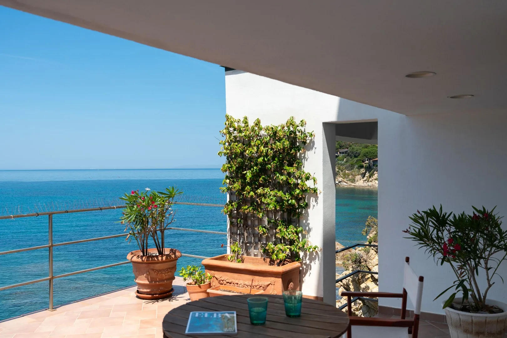 A sea-facing terrace with potted plants and a view of the water.