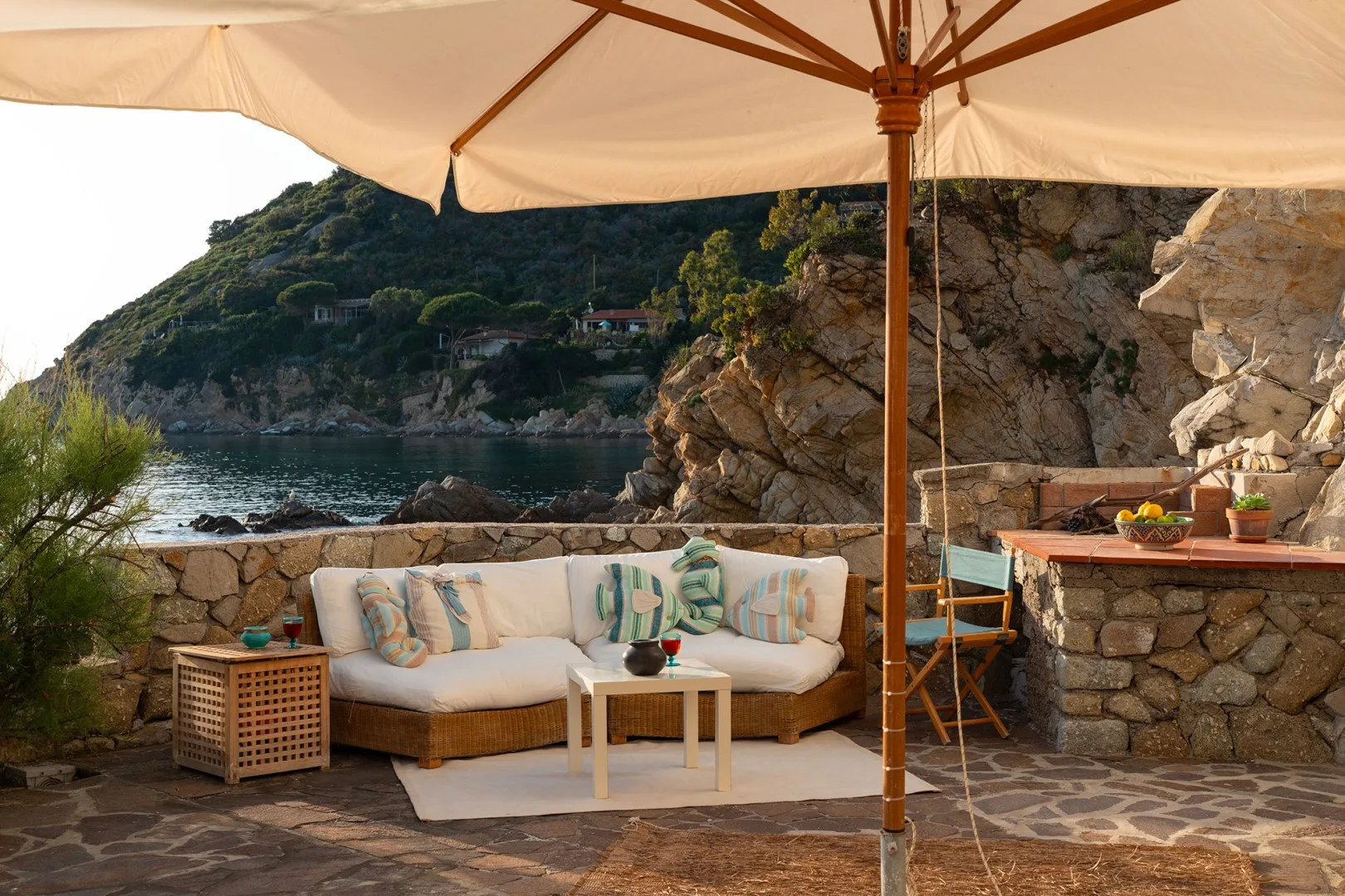 A seaside patio with cushioned seating beneath a large umbrella.