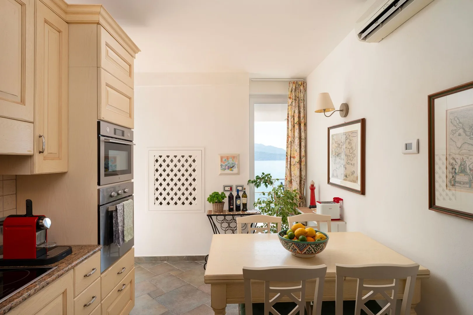 A dining area with a table and fruit bowl beside the kitchen.