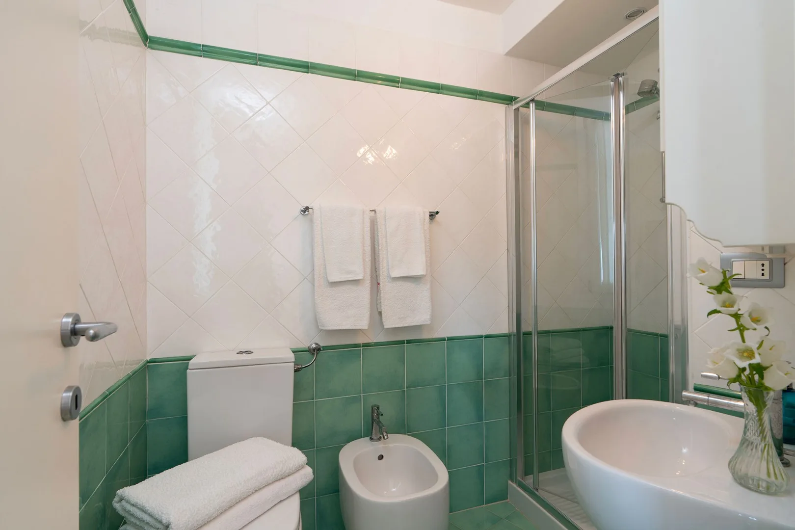 A tiled bathroom with a glass shower and white bathroom fixtures.