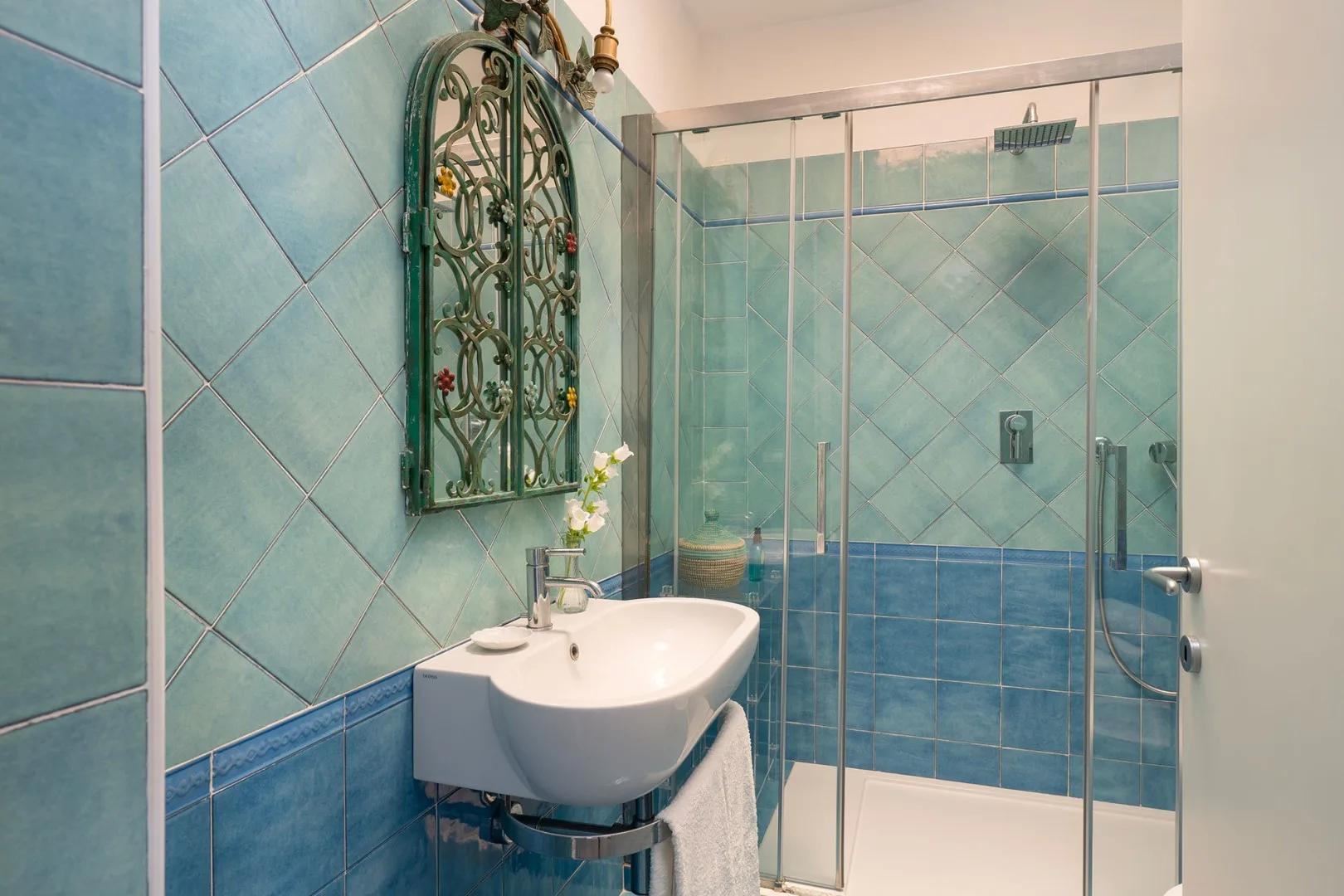 A tiled bathroom with a sink and glass shower.
