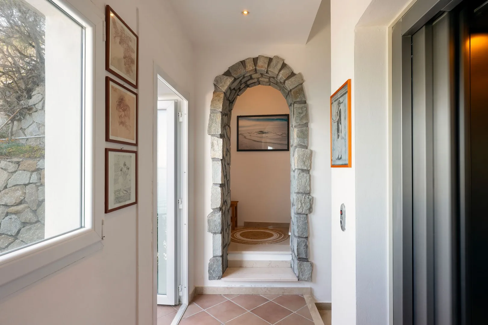 A bright hallway with a stone archway and framed artwork.