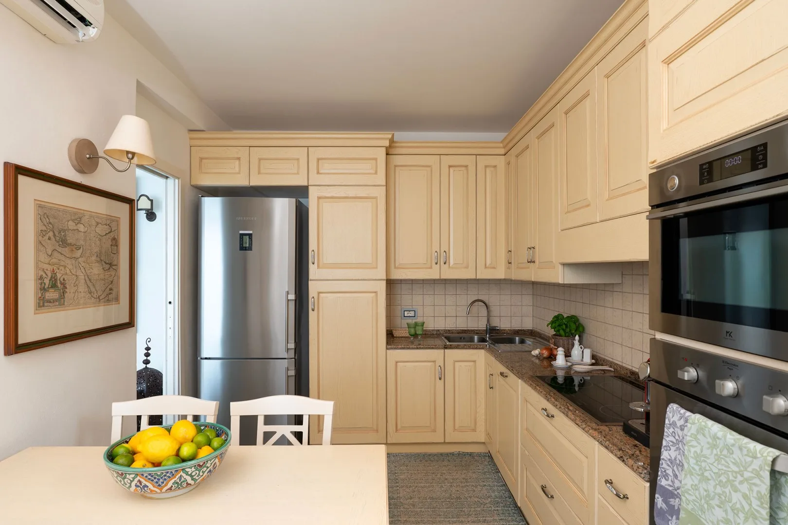 A bright kitchen with pale cabinetry, a counter, and a dining table.