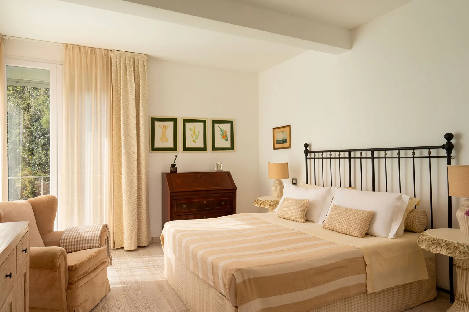 A bedroom with a large bed, striped bedding, and tall windows with curtains.