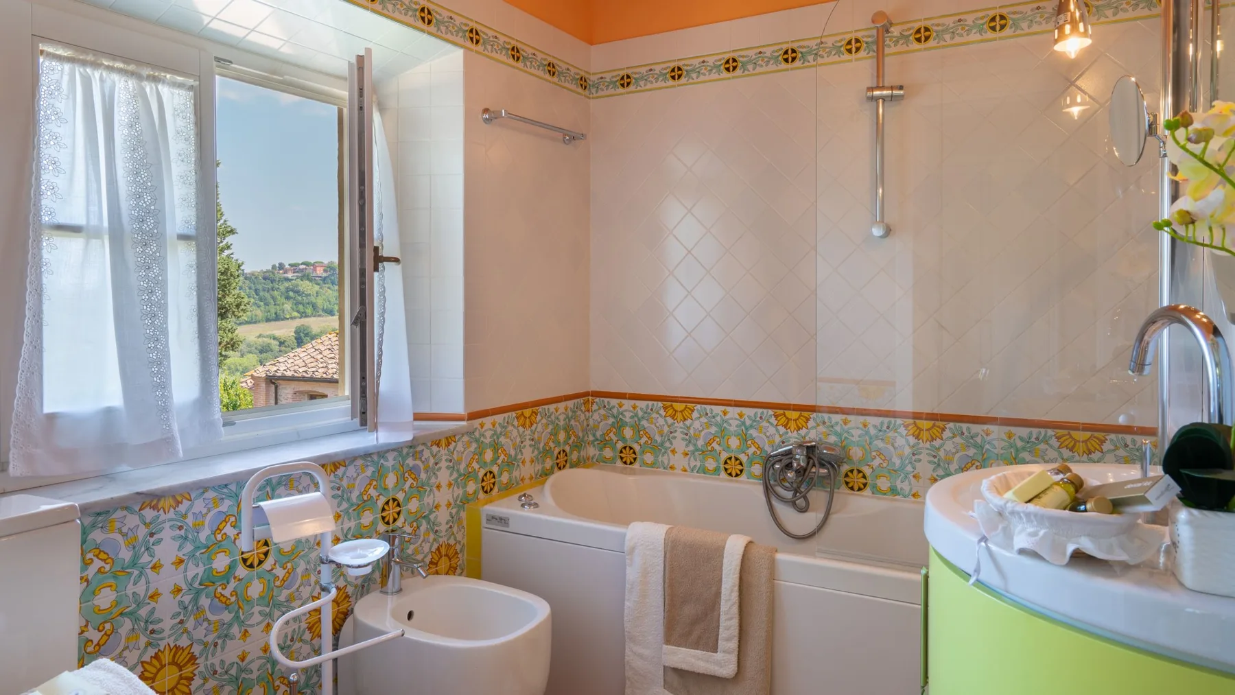 Un baño con bañera, bidé y lavabo junto a una ventana abierta.