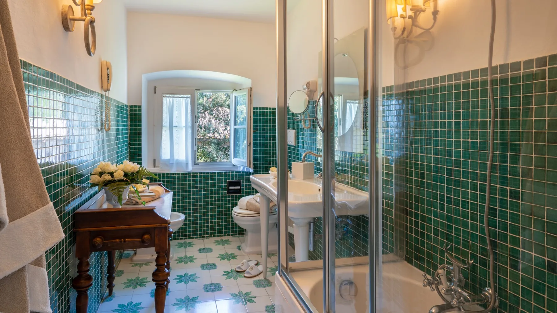 Un baño con azulejos, ventana, lavabo, inodoro y ducha de vidrio.