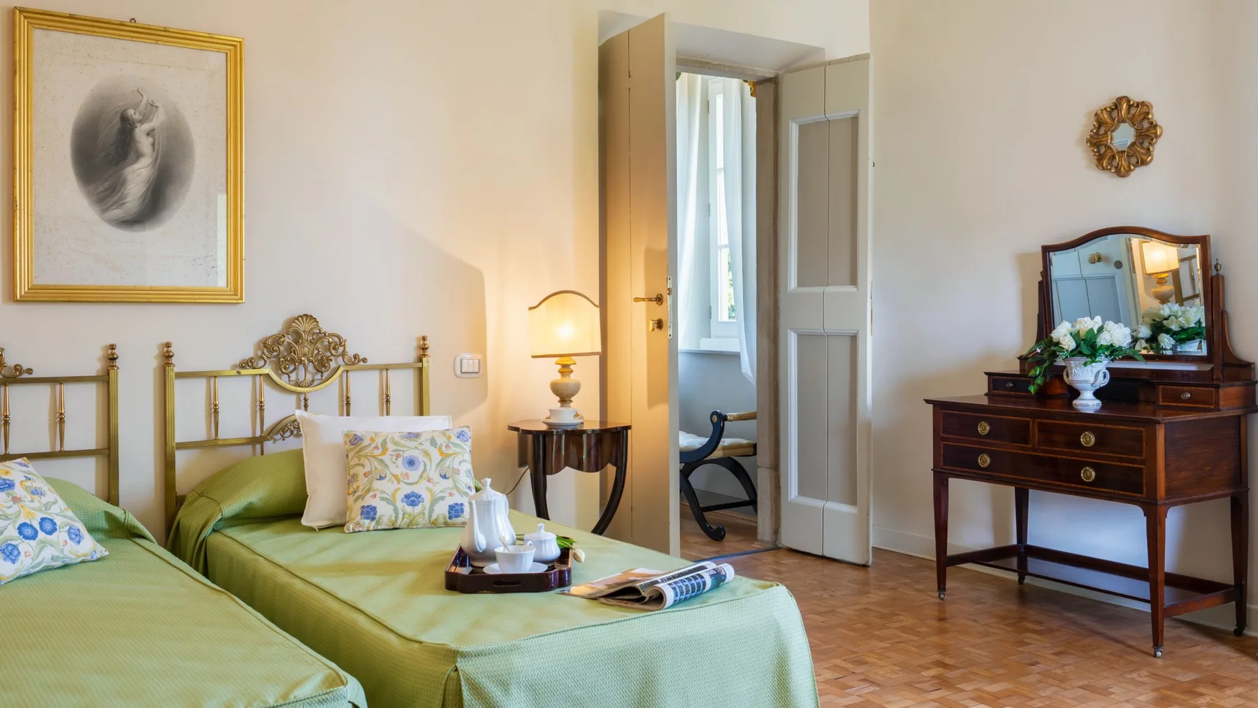 Un dormitorio con camas cubiertas de verde y una cómoda de madera con espejo.