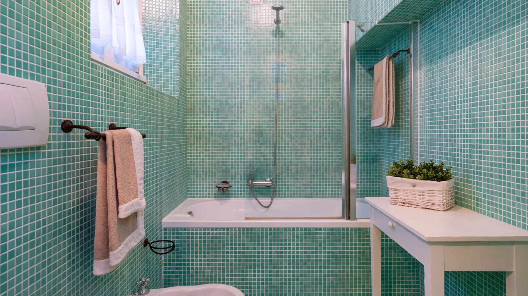 Un baño alicatado con bañera, ducha y toallero.