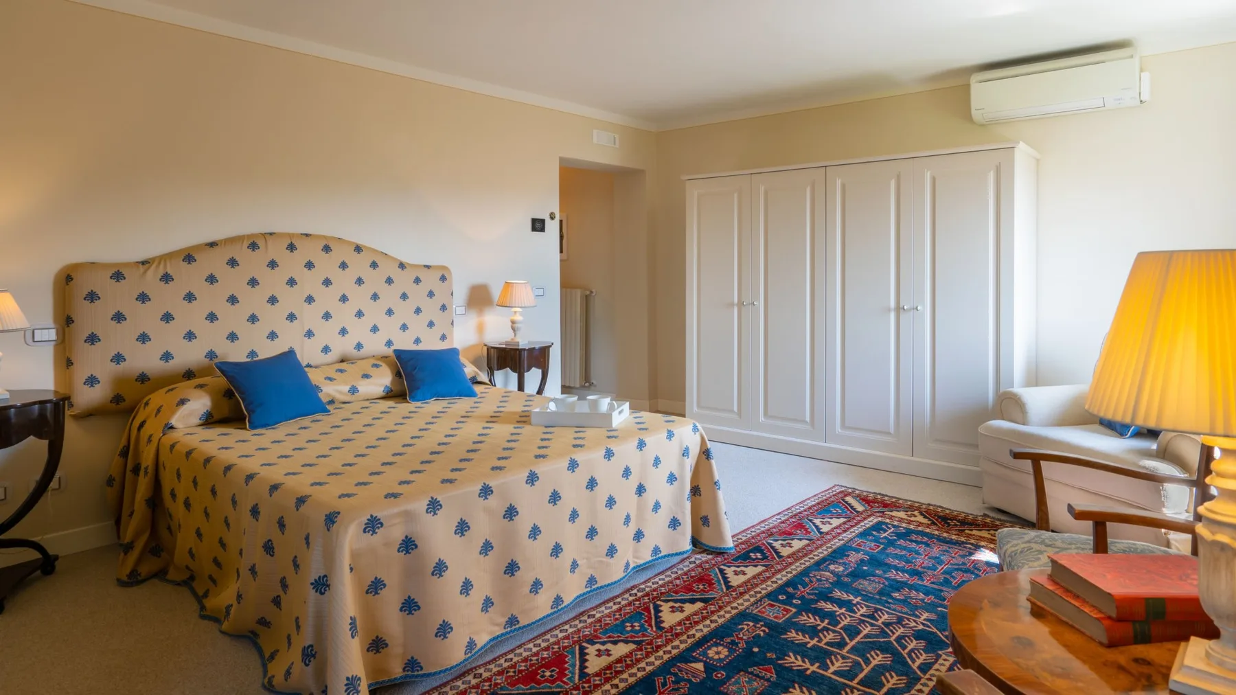 Un dormitorio con una cama estampada, armarios blancos y una alfombra colorida.
