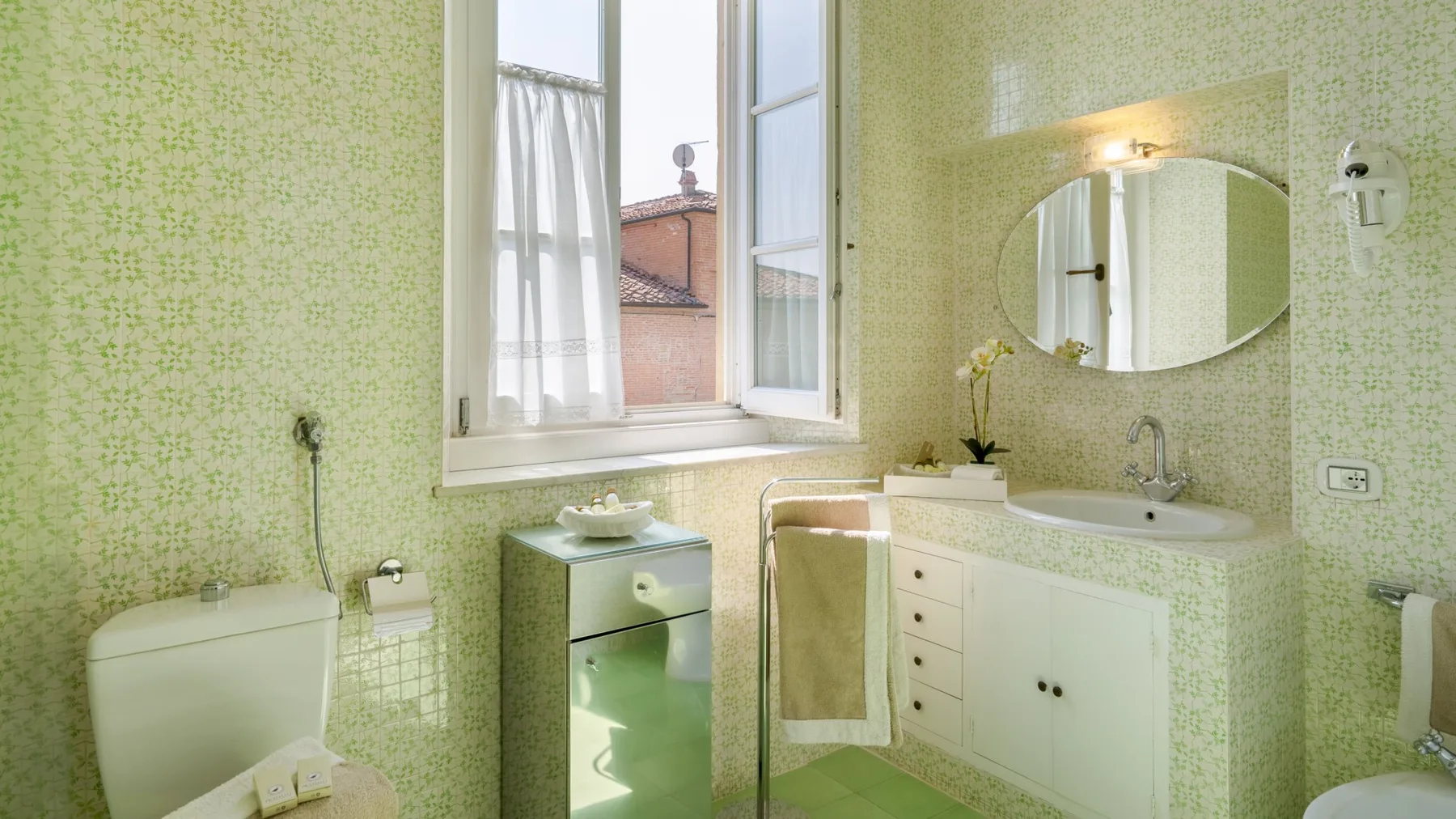 Un baño con lavabo, espejo y una ventana abierta.