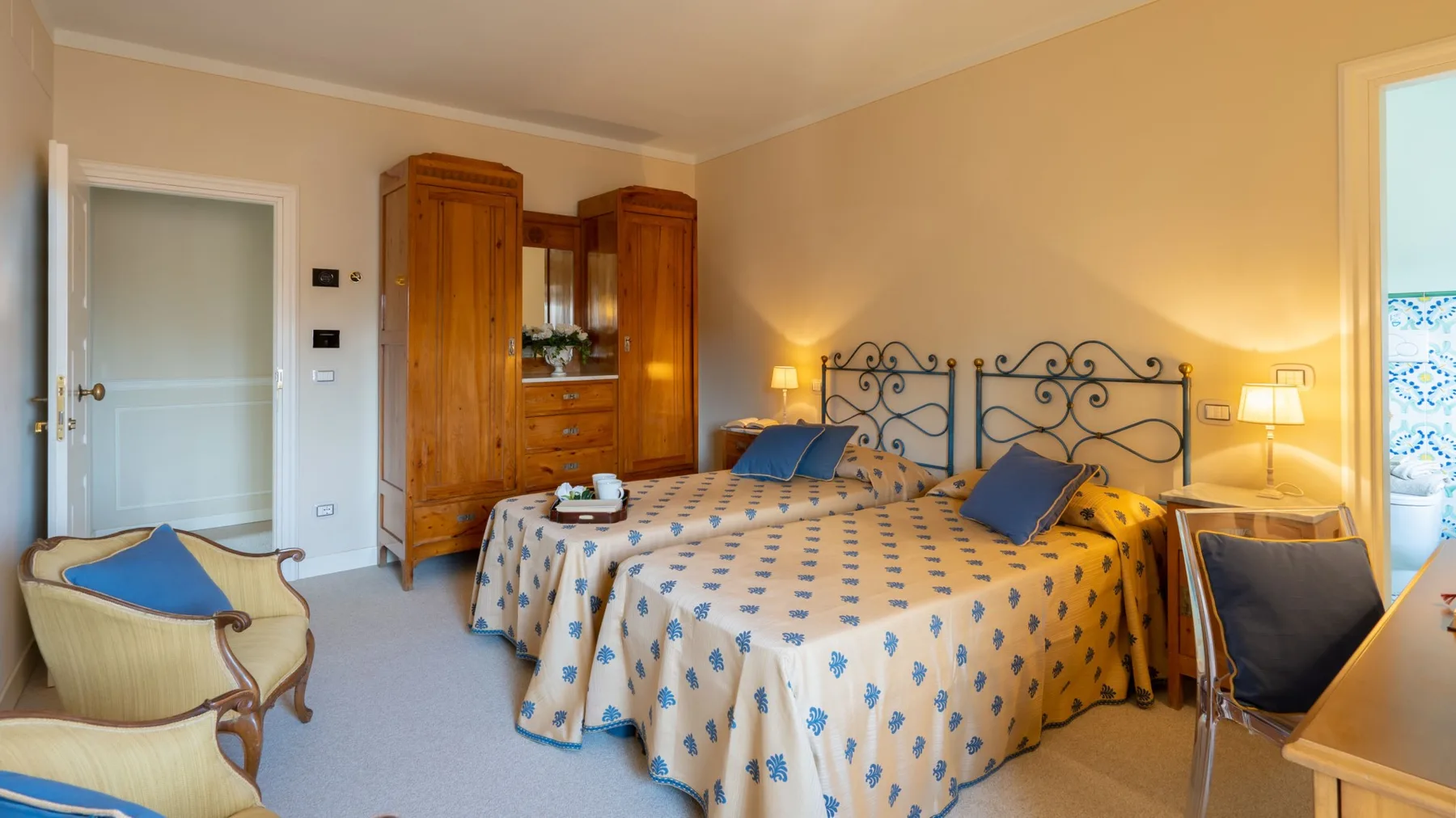 Dormitorio con dos camas, colchas estampadas y un armario de madera.