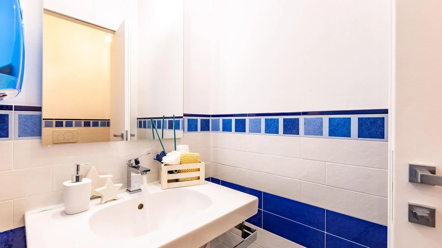 A bathroom vanity with a white sink and blue tile accents.