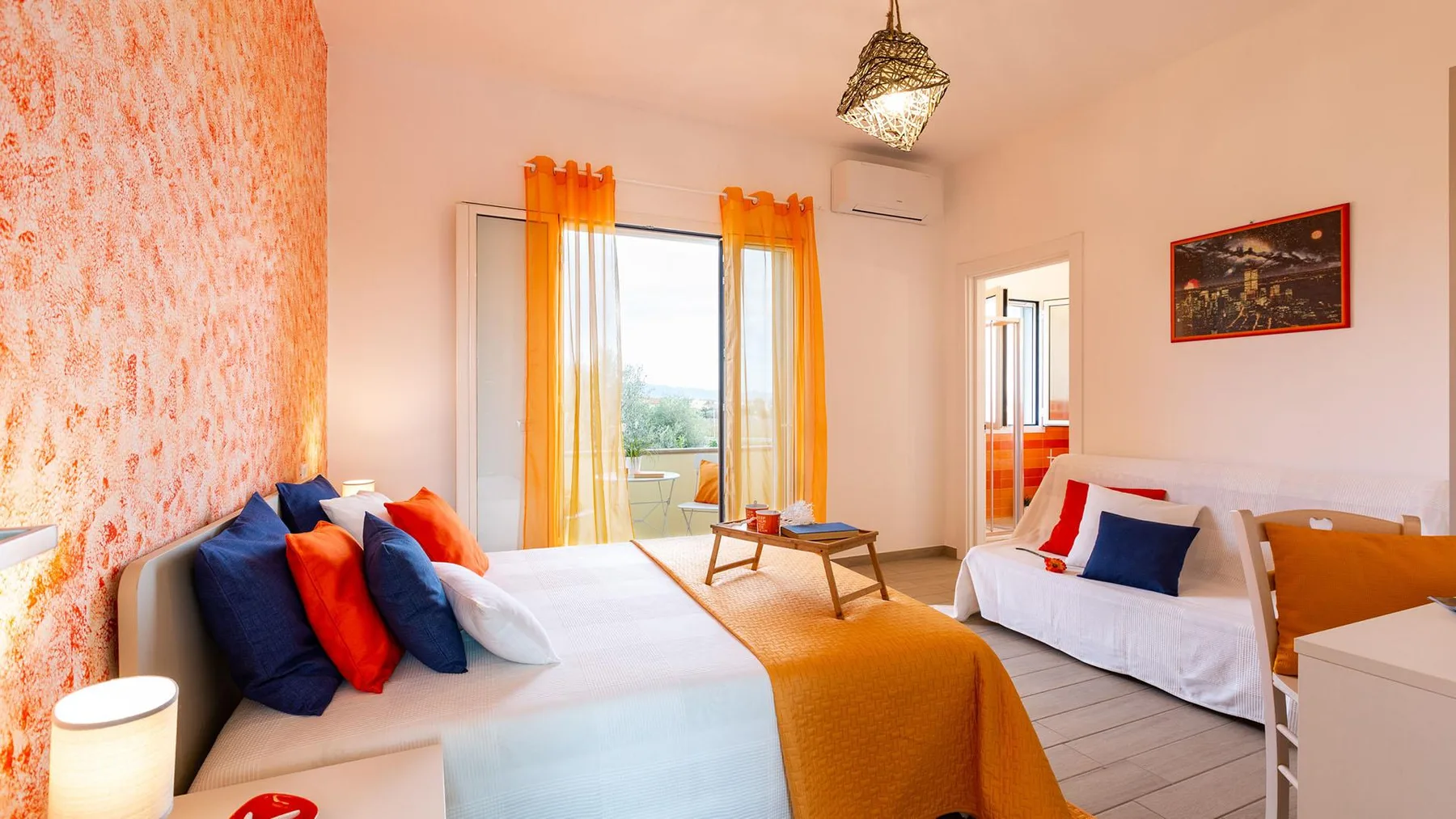 A bright bedroom with two beds, orange curtains, and a small table.