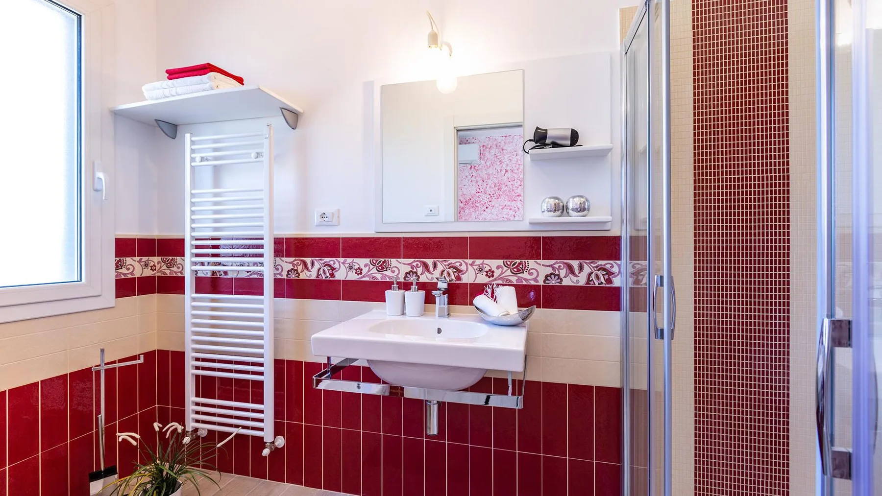A tiled bathroom with a wall-mounted sink and glass shower.