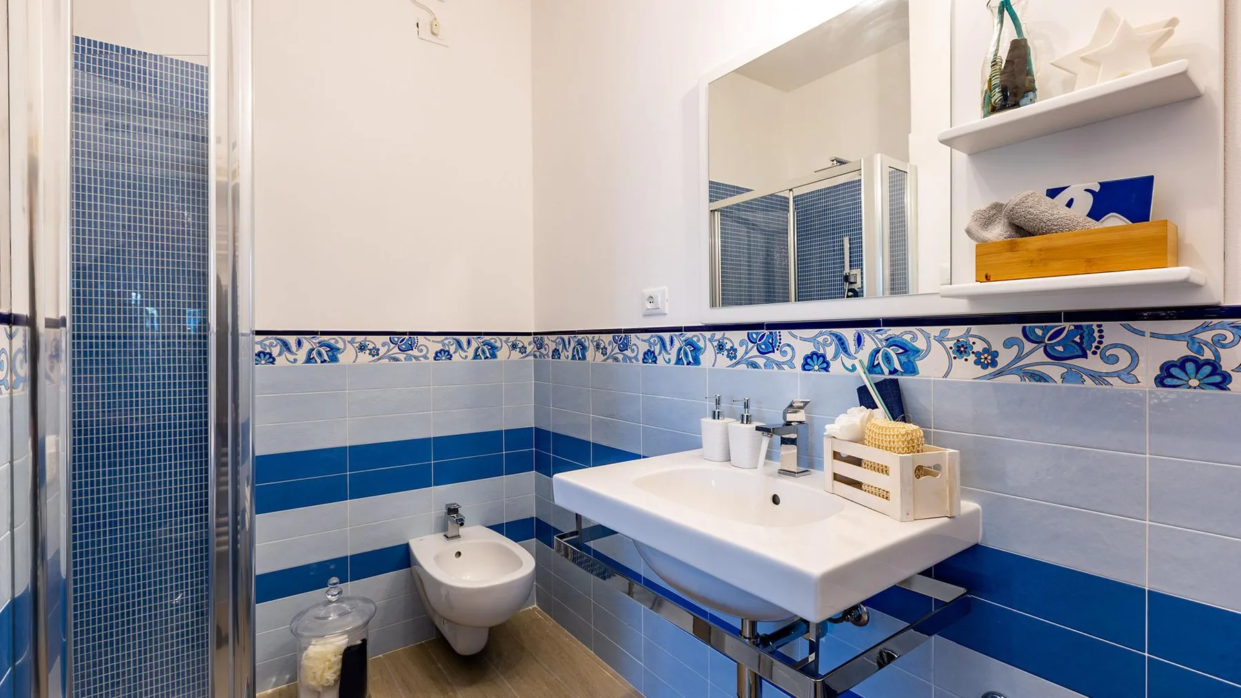 A tiled bathroom with a sink, mirror, and glass shower.