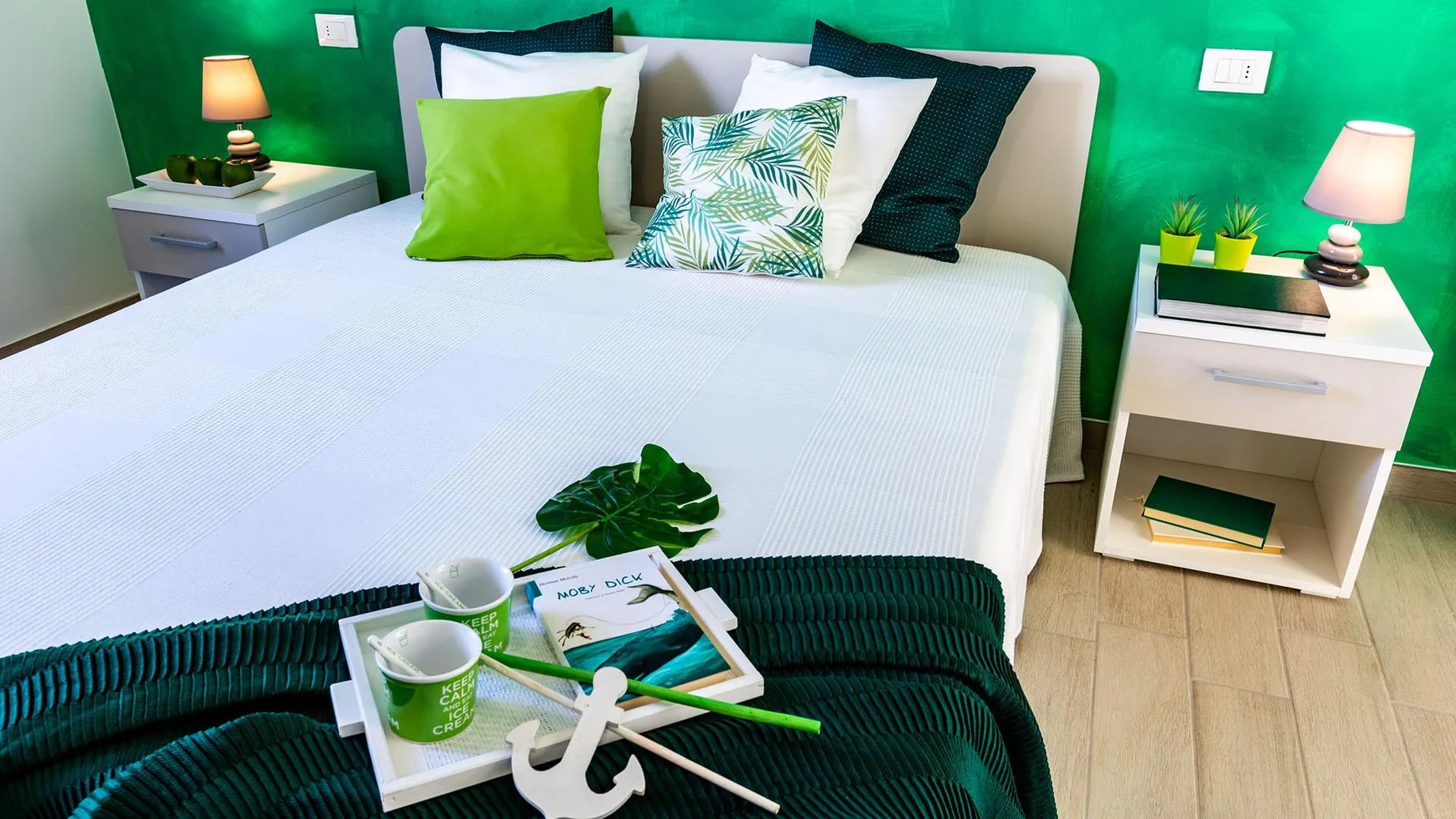 A bedroom with a neatly made bed, colorful pillows, and matching bedside tables.