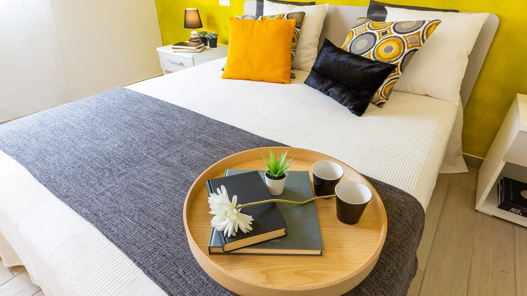 A bedroom with a bed, colorful pillows, and a round tray on the bed.
