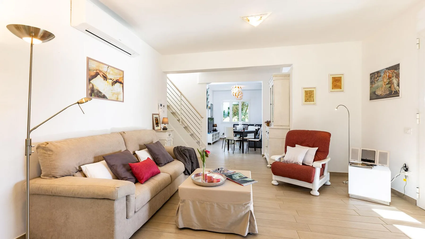 A living room with seating around a coffee table and a dining area beyond.
