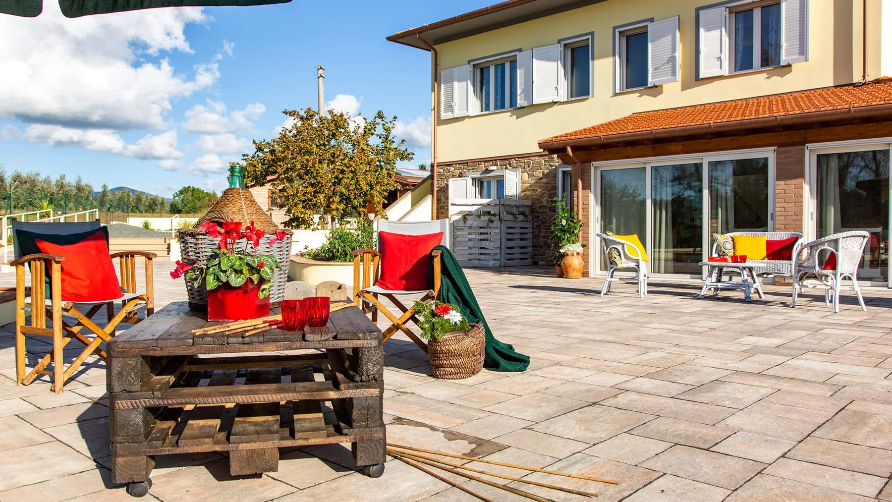 A paved outdoor patio beside a house, with seating and a small slide.