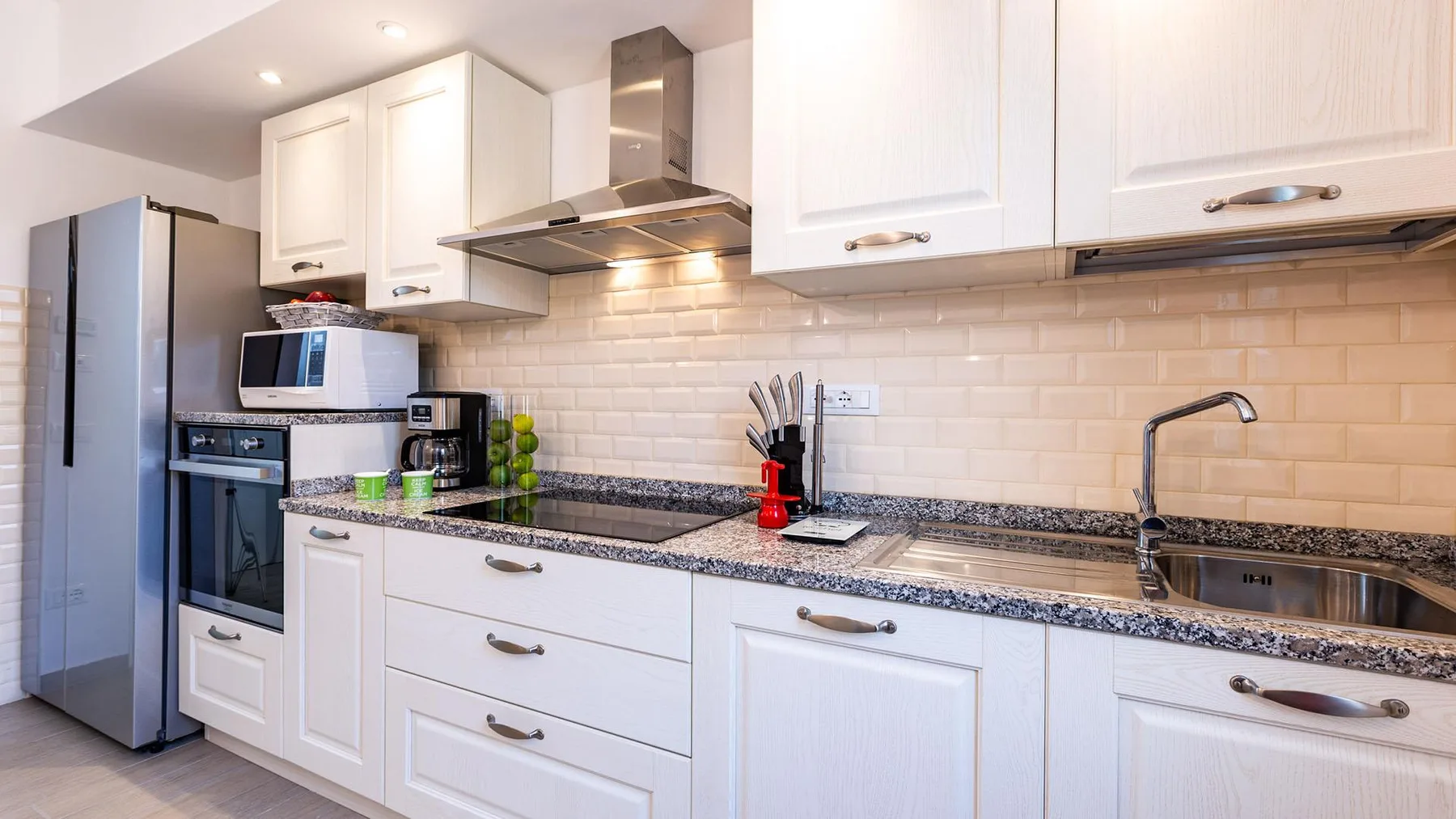 A bright kitchen with white cabinets, a countertop, and a sink.