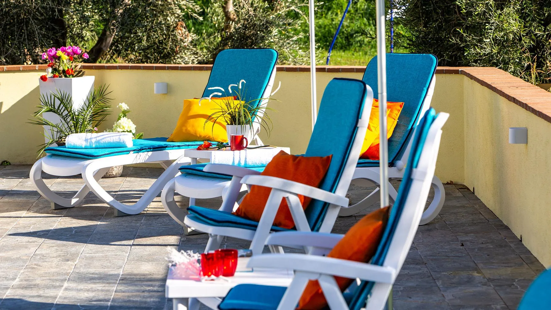 An outdoor patio with blue lounge chairs and colorful cushions.