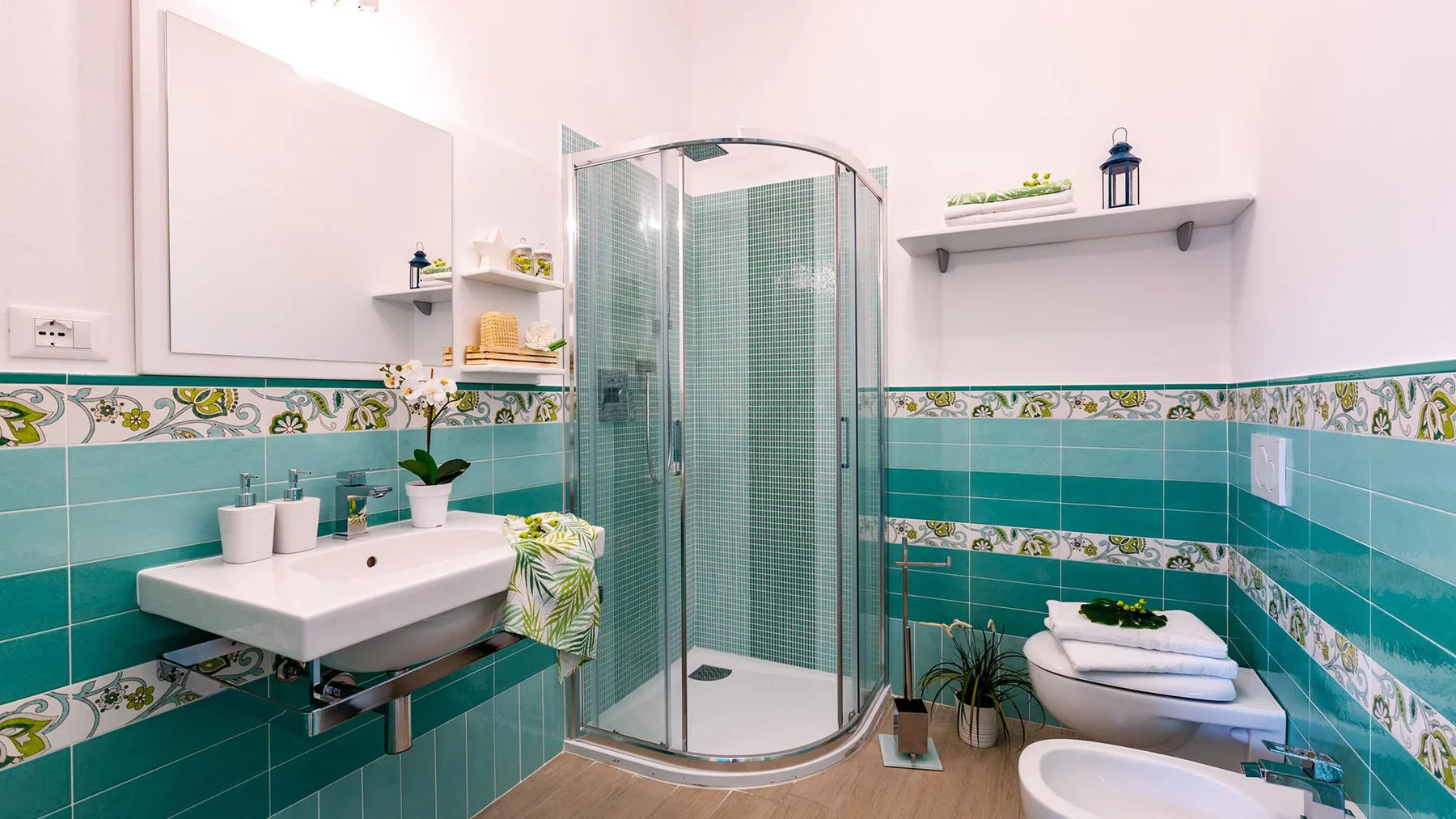 A tiled bathroom with a glass shower and a sink.