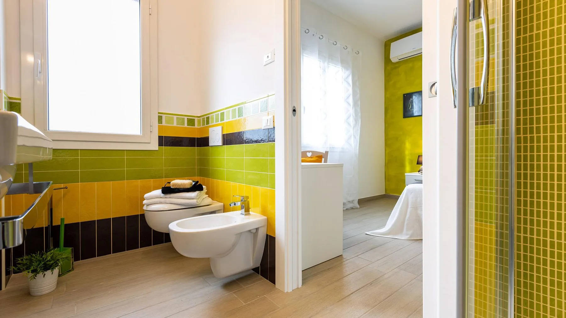 A bathroom with a wall-mounted sink and toilet beside a glass shower.