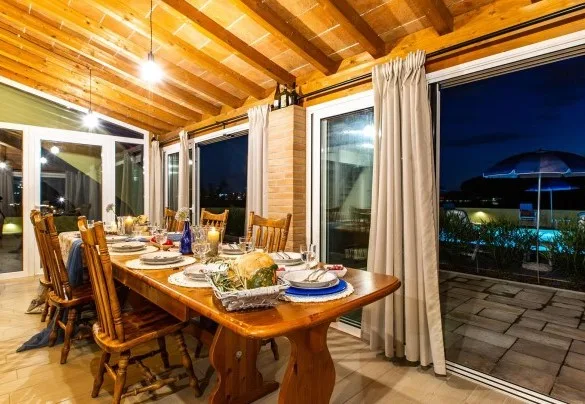 A dining area with a long table set for a meal beside large glass doors.