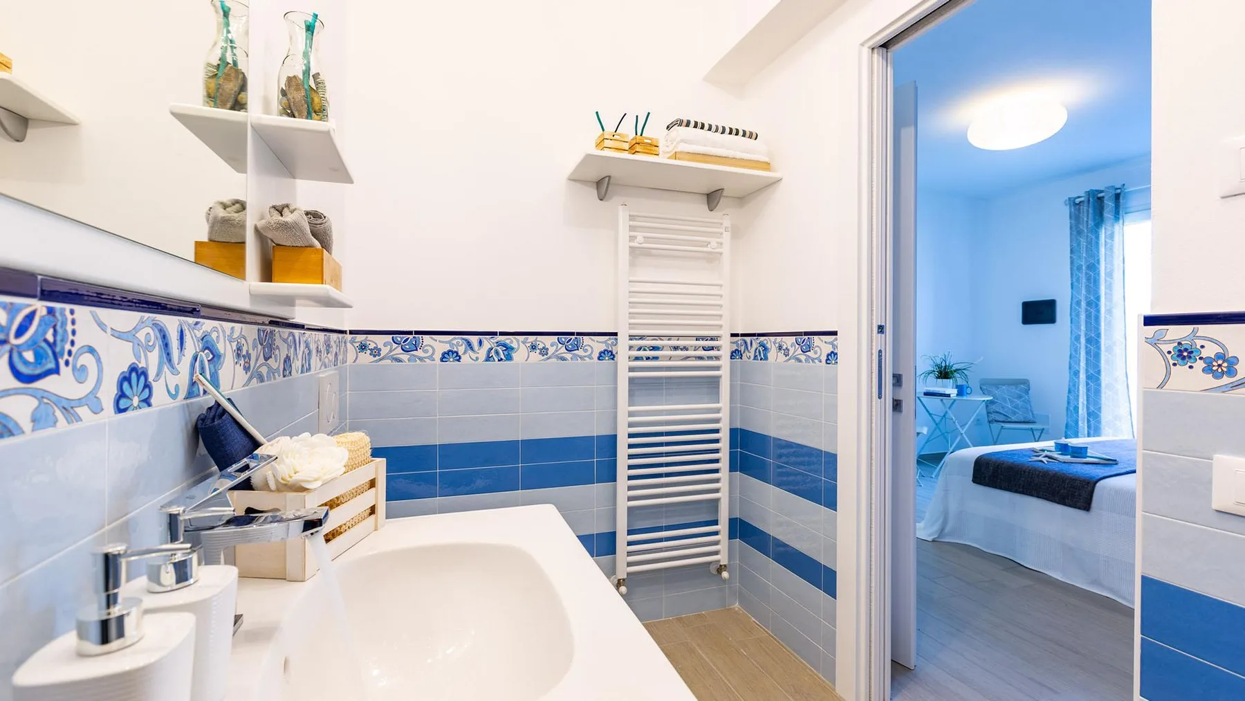 A tiled bathroom with a sink and a doorway opening onto a bedroom.