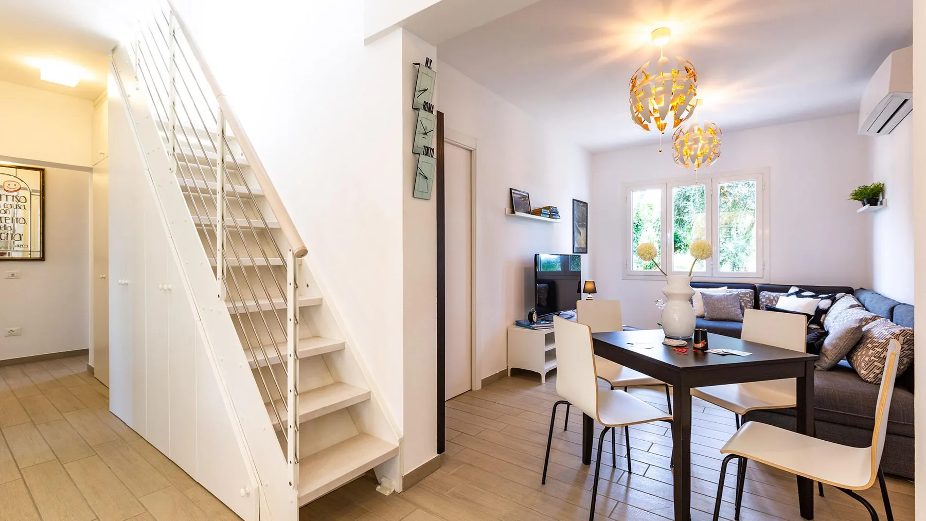A bright dining and living area with a table, seating, and a staircase.