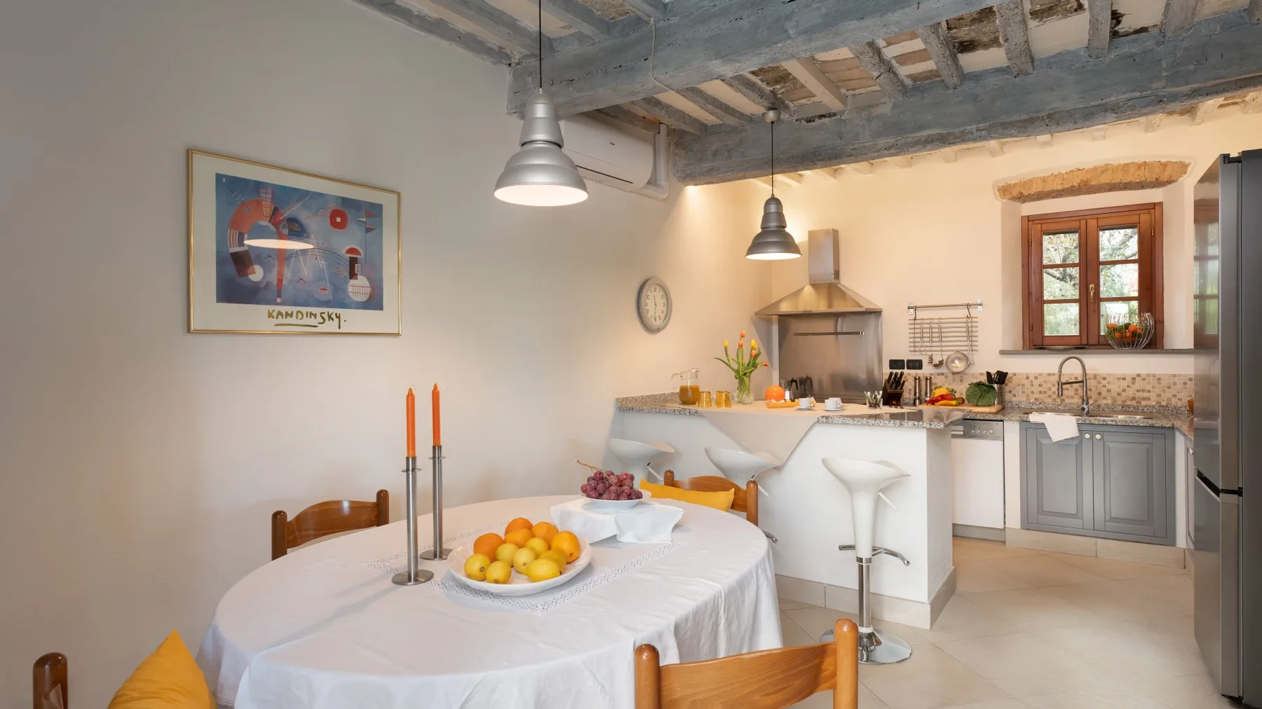 Comedor junto a una cocina abierta, con una mesa redonda y lámparas colgantes.