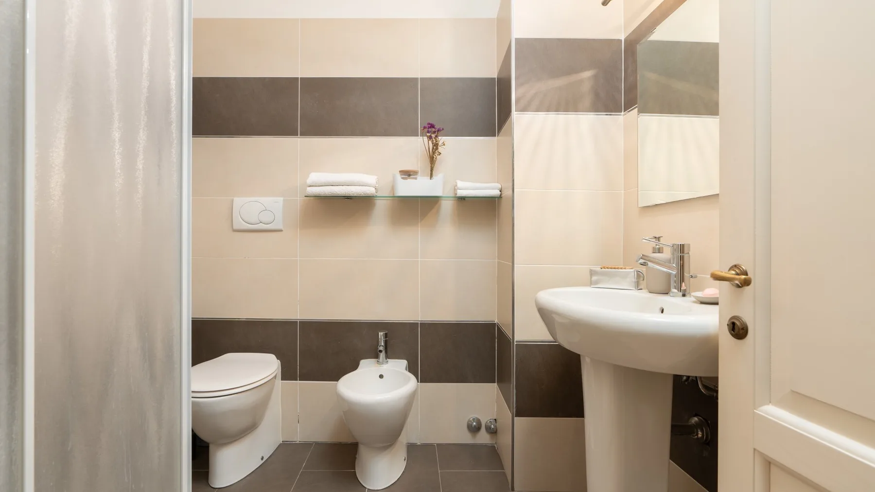 Un baño alicatado con inodoro, bidé y lavabo.