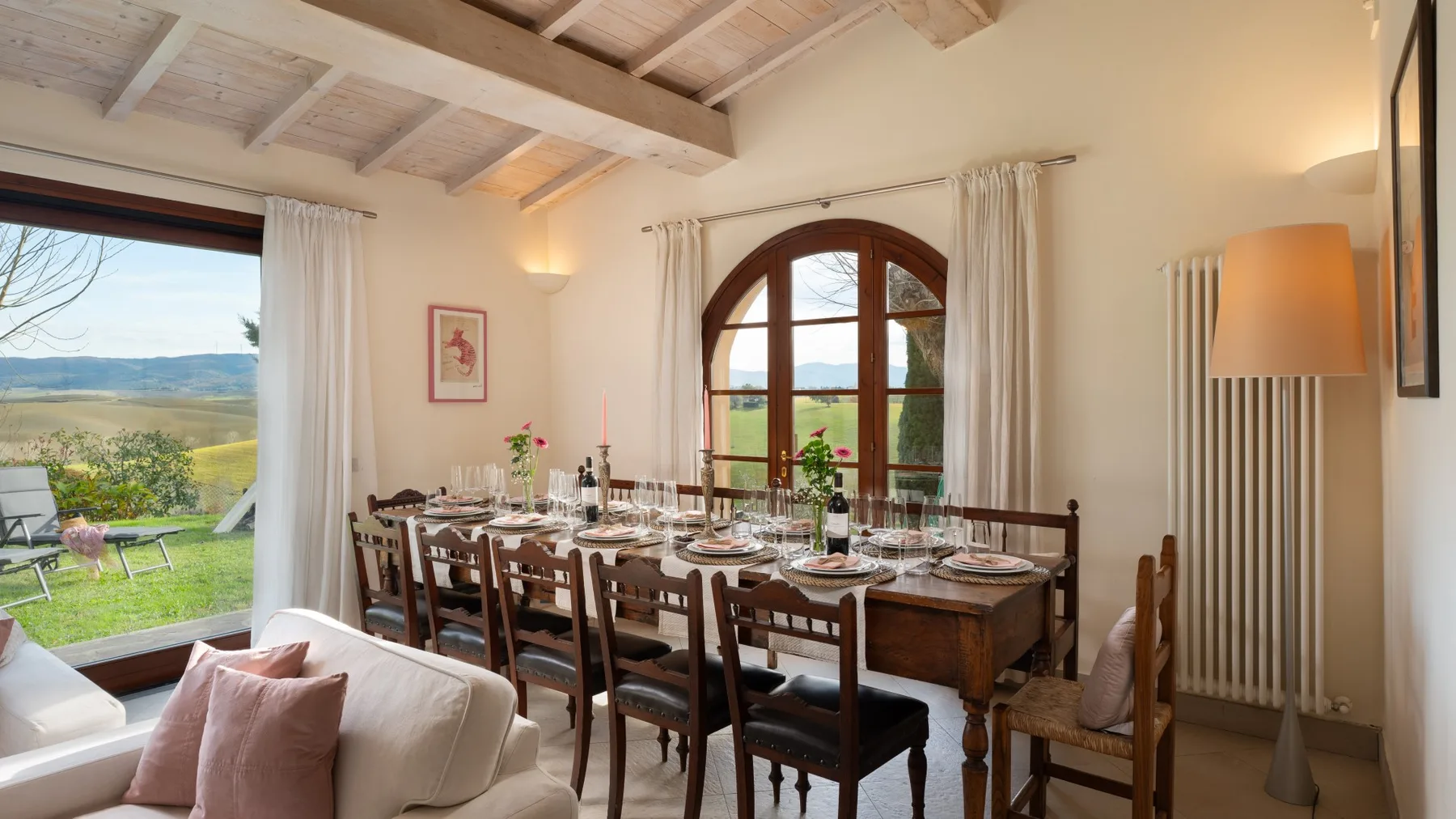 Comedor con la mesa puesta junto a una gran ventana arqueada.