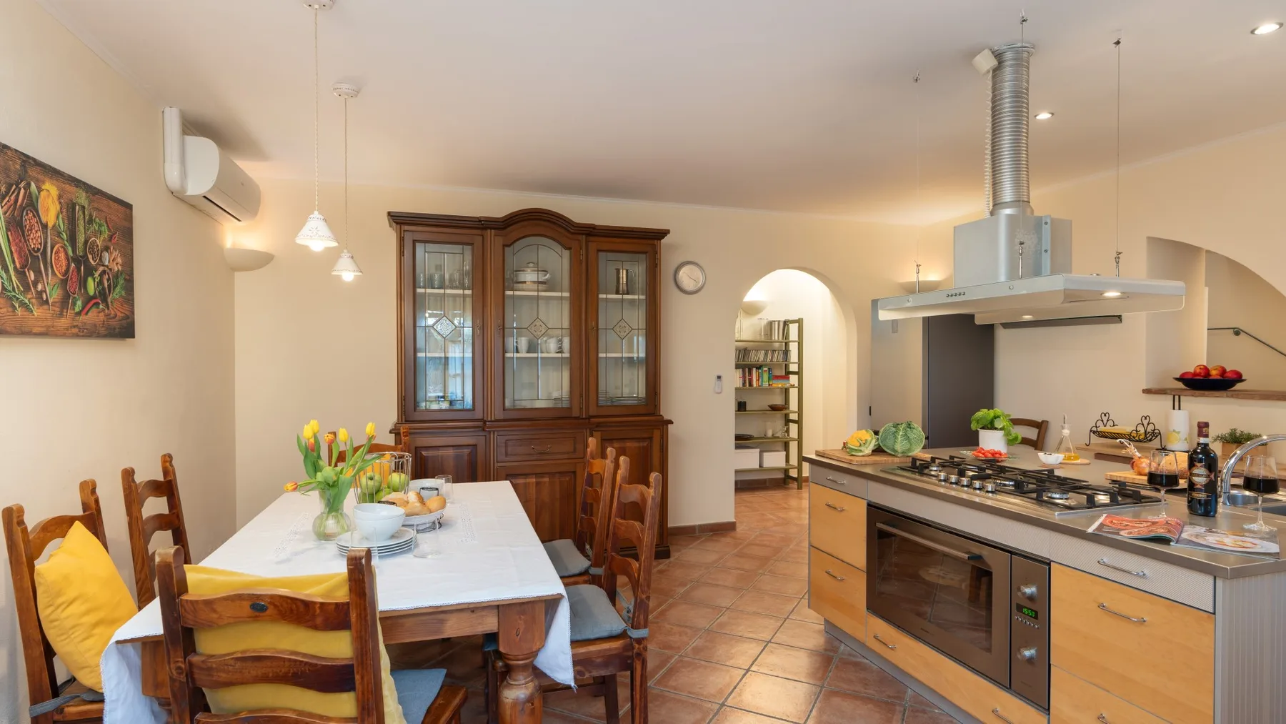 Comedor junto a una cocina, con una mesa puesta y un mueble de madera.