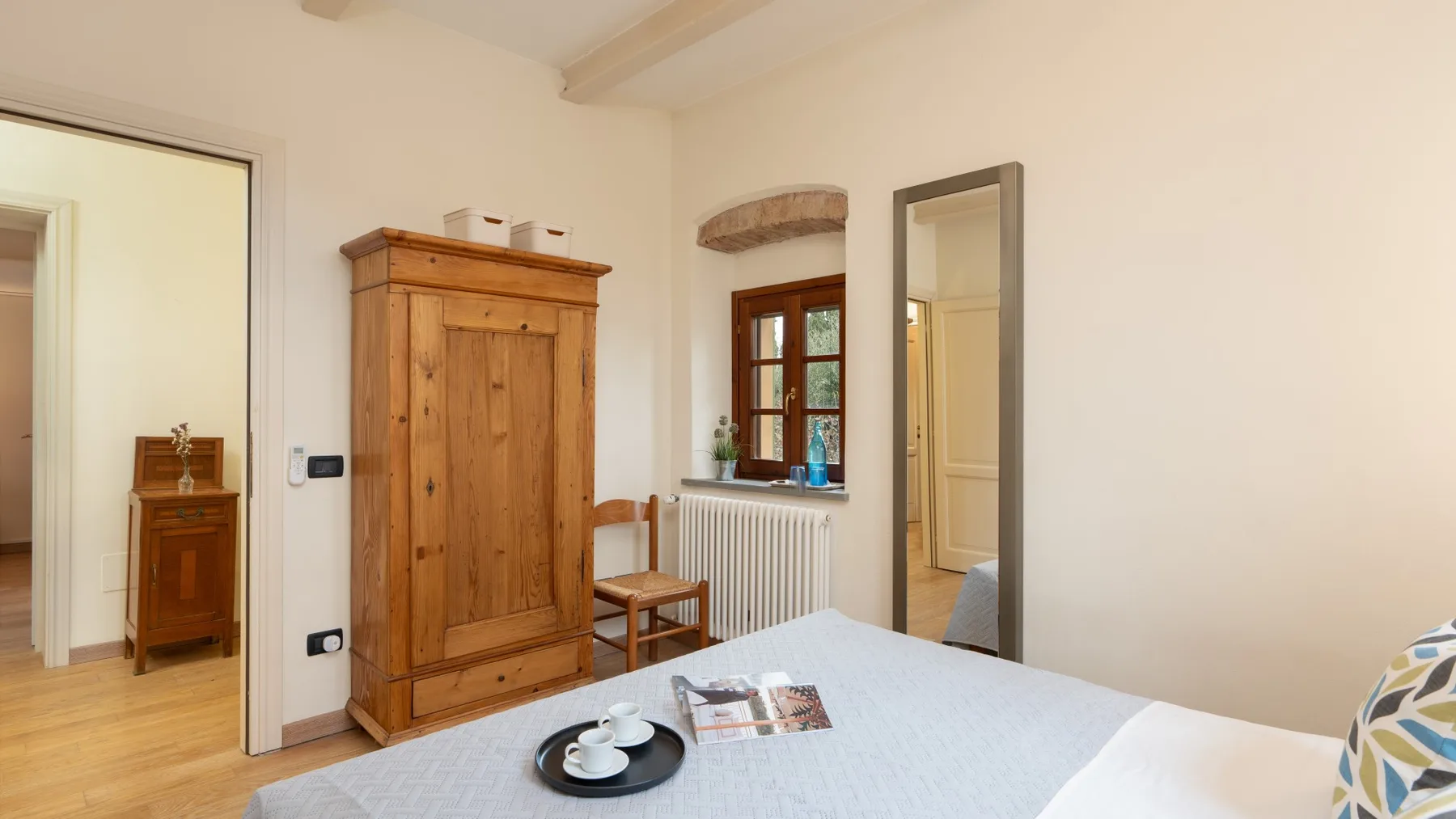 Un dormitorio luminoso con un armario de madera y una cama junto a una ventana.