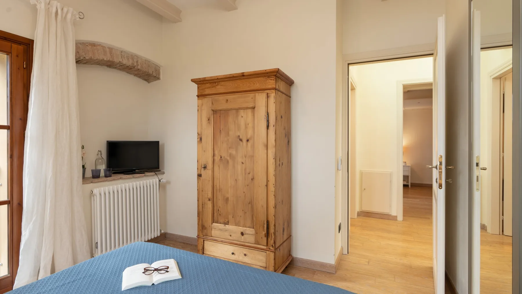 Un dormitorio con un armario de madera, un televisor y una puerta abierta.