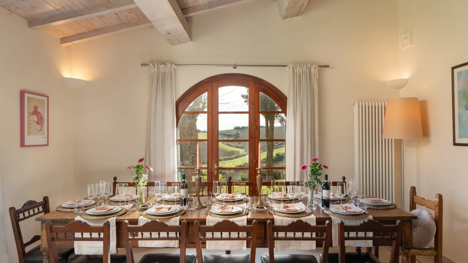 Un comedor con una mesa larga preparada para comer junto a una ventana arqueada.